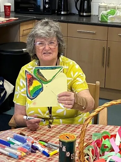 A lady proudly holding up her craft work